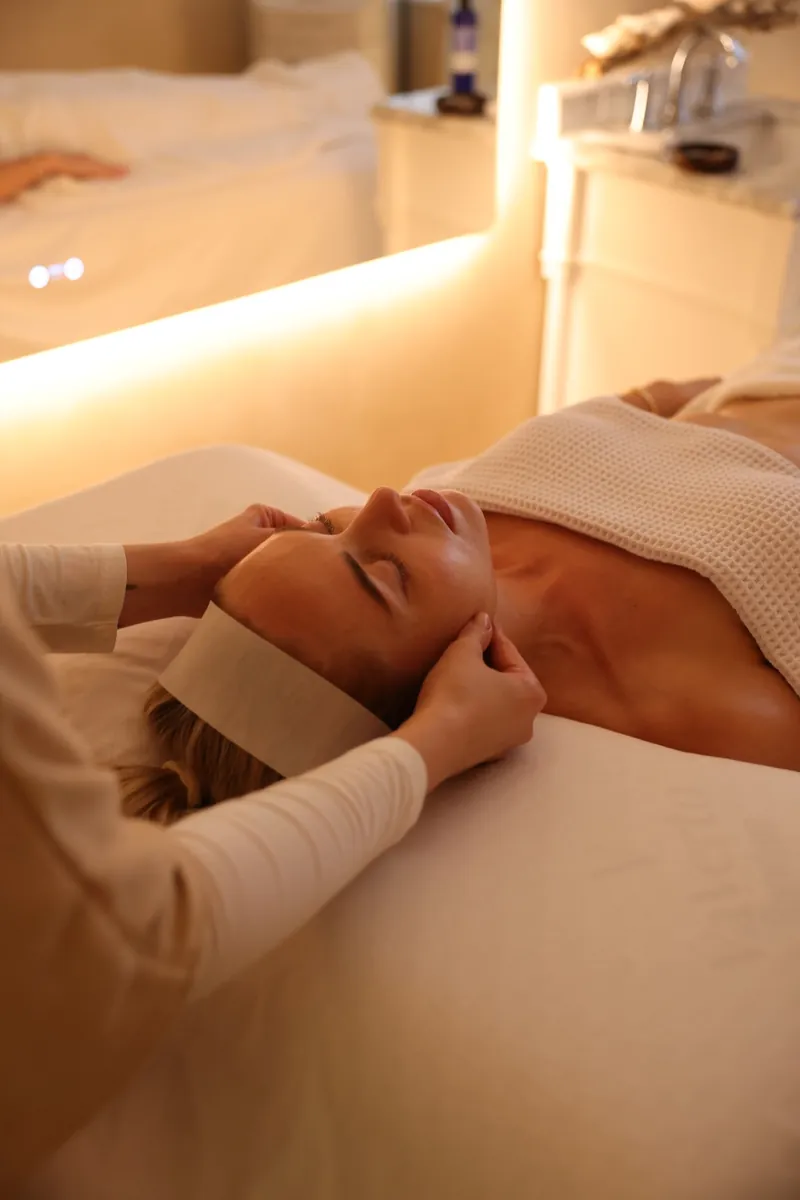 Hands gently massaging the jaw and neck during a facial session