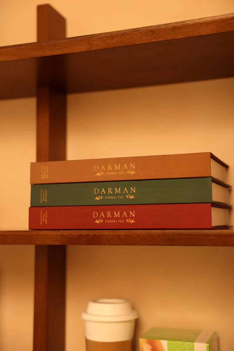 Book-shaped herbal tea boxes on a wooden shelf at LIMFAERA